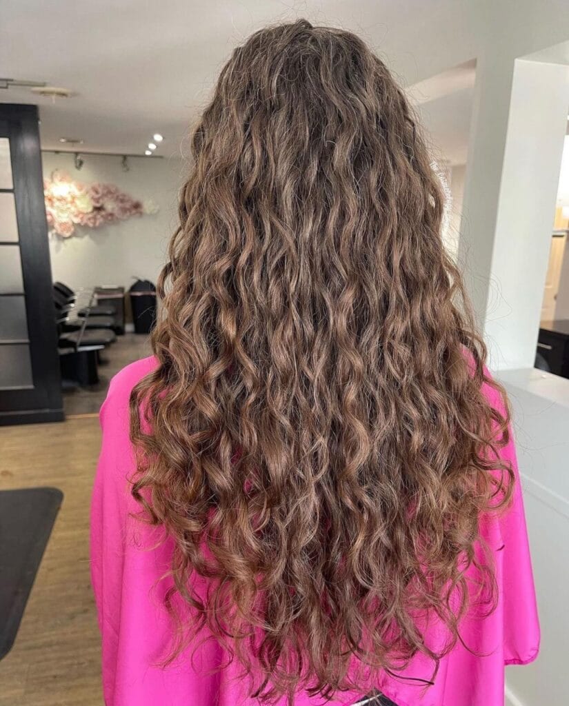 A person with long, wavy brown hair visits YOLOve Beauty Spa in Dartmouth, enjoying a modern salon with clean and well-lit surroundings. The spa offers rejuvenating experiences with skilled stylists in a relaxing atmosphere.