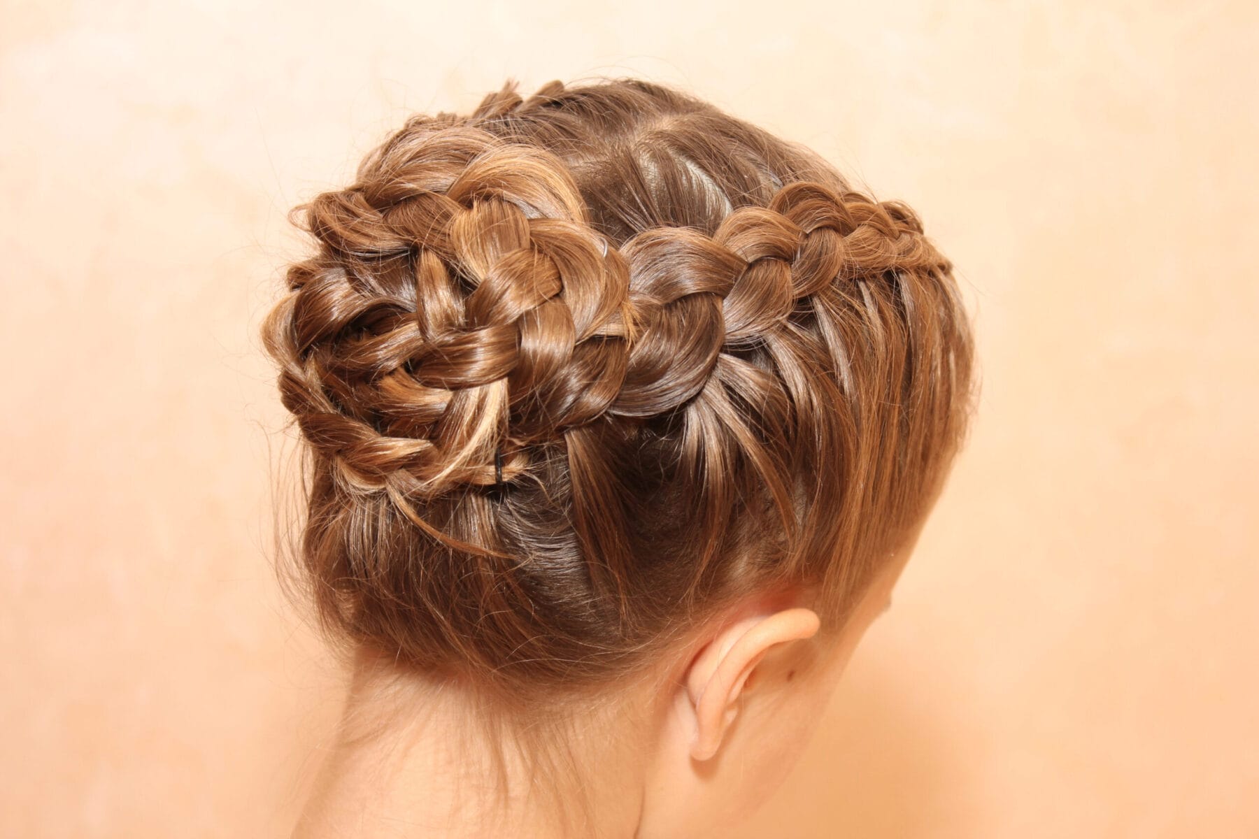 Experience the elegance at YOLOve Beauty Spa in Dartmouth. This image showcases an intricate braided updo, styled to perfection by our expert stylists. Each braid is meticulously woven into a stunning circular pattern, highlighting attention to detail and craftsmanship. The soothing peach background enhances the sophistication of the hairstyle, offering a glimpse into the transformative and luxurious services you'll enjoy during your visit.